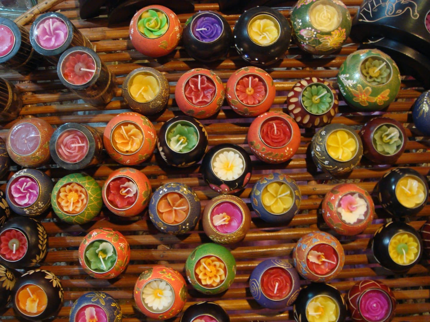 Candele colorate a forma di fiore sono disposte in piccoli portacandele rotondi.