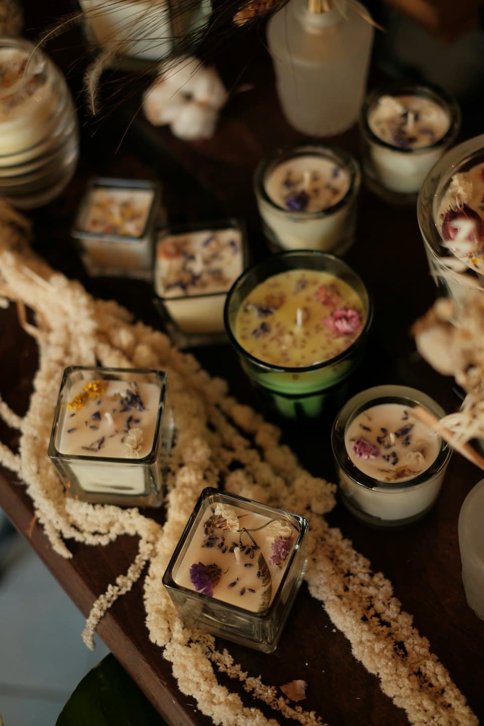 Candele artigianali in cera di soia con fiori secchi su legno.