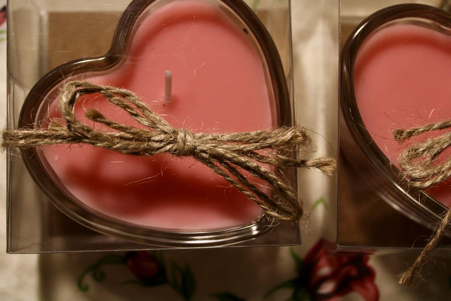 Due candele a forma di cuore rosa legate con fiocchi di spago rustico.
